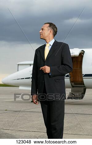 Businessman standing in front of a private airplane View Large Photo Image Stock Photo - Businessman standing in front of a private airplane. Fotosearch