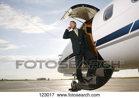 Stock Photo - Businessman standing on a private airplane’s steps. Fotosearch