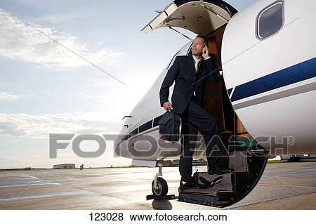 Stock Photo - Businessman standing on a private airplane’s steps. Fotosearch