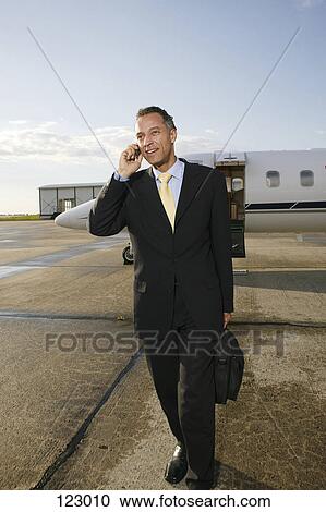 Businessman with cell phone standing in front of a private airplane View Large Photo Image Stock Image - Businessman with cell phone standing in front of a private airplane. Fotosearch