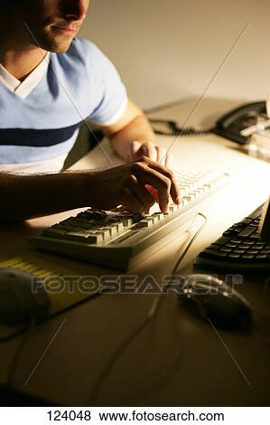Man sitting at an office desk, typing View Large Photo Image Stock Photo - Man sitting at an office desk, typing. Fotosearch