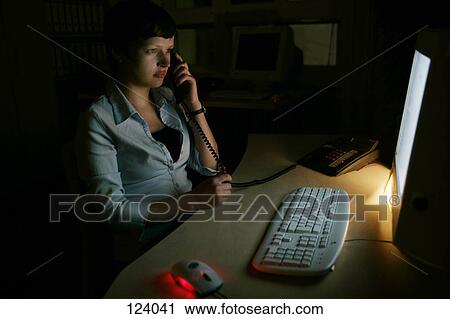 Stock Image - Woman on telephone, sitting at a desk. Fotosearch