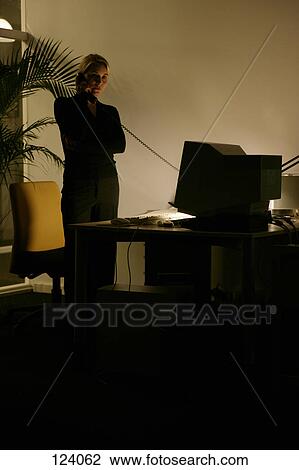 Woman on telephone, standing next to an office desk View Large Photo Image Stock Image - Woman on telephone, standing next to an office desk. Fotosearch