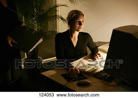 Woman sitting at a computer in an office View Large Photo Image Stock Image - Woman sitting at a computer in an office. Fotosearch