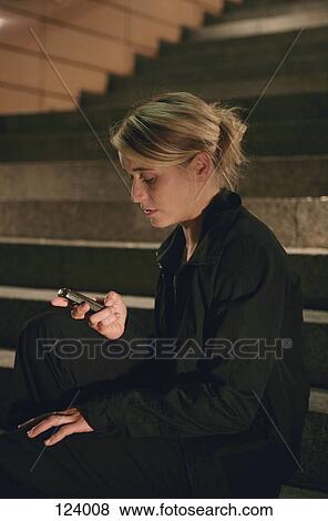 Woman sitting on stairs with mobile phone View Large Photo Image Stock Photo - Woman sitting on stairs with mobile phone. Fotosearch