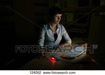 Stock Image - Woman using a computer in the dark. Fotosearch