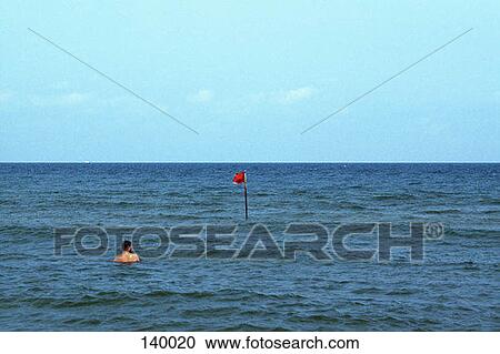 A man in the ocean near a buoy View Large Photo Image Stock Image - A man in the ocean near a buoy. Fotosearch