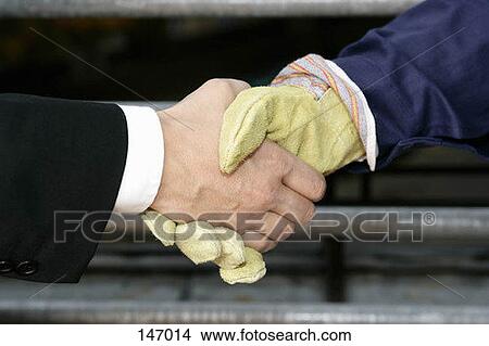 A business man and a construction worker shaking hands View Large Photo Image Picture - A business man and a construction worker shaking hands. Fotosearch