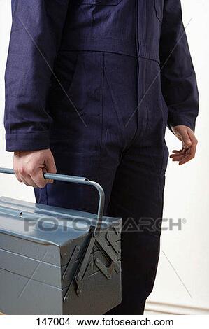 Picture - A man in a worker suit carrying a tool box. Fotosearch