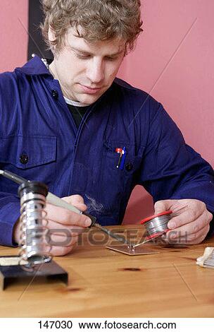 Stock Image - A man working with a soldering iron. Fotosearch