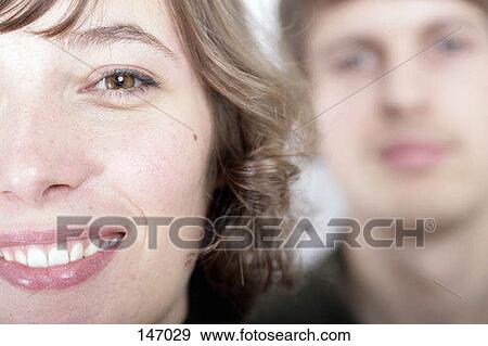 Close up of a young woman with a man blurred in the background View Large Photo Image Stock Photo - Close up of a young woman with a man blurred in the background. Fotosearch