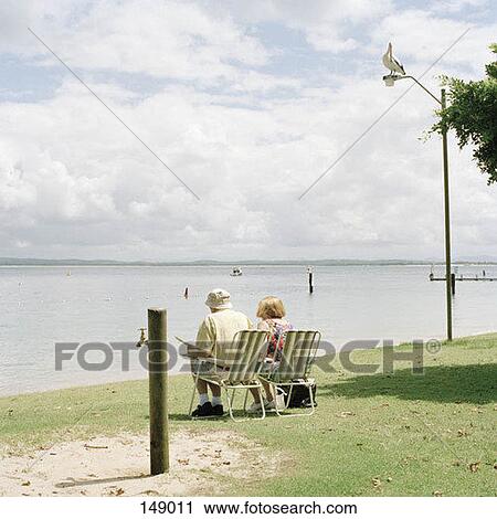 A senior couple sitting in chairs near the seashore View Large Photo Image Stock Image - A senior couple sitting in chairs near the seashore. Fotosearch