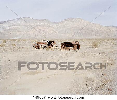 Stock Photo - Two abandoned cars in a desolate landscape. Fotosearch