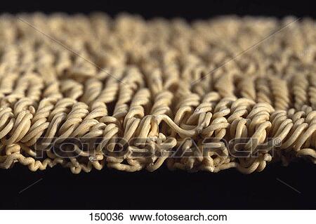 Stock Photograph - Close up of Uncooked Ramen noodles on a black surface. Fotosearch