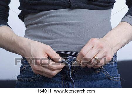 Stock Image - Midsection of a woman buttoning her jeans. Fotosearch