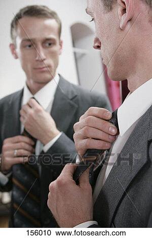 A man straightening his tie in a mirror View Large Photo Image Stock Image - A man straightening his tie in a mirror. Fotosearch