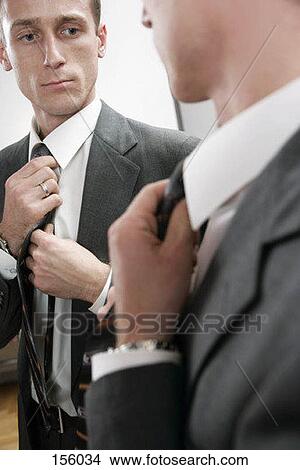 A man straightens his tie in a mirror View Large Photo Image Picture - A man straightens his tie in a mirror. Fotosearch
