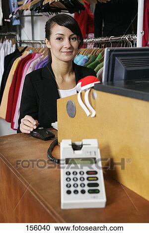A woman sitting at the cash register of a clothing store, smiling View Large Photo Image Stock Image - A woman sitting at the cash register of a clothing store, smiling. Fotosearch