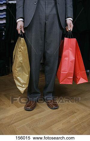Front view of a man in formal attire holding three shopping bags View Large Photo Image Stock Photography - Front view of a man in formal attire holding three shopping bags. Fotosearch