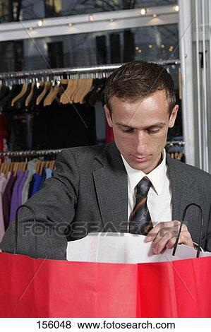 Front view of a man reaching into a shopping bag View Large Photo Image Stock Photo - Front view of a man reaching into a shopping bag. Fotosearch