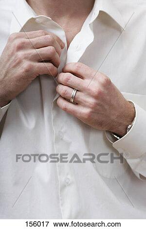 Stock Photo - Midsection of a man unbuttoning a white shirt. Fotosearch