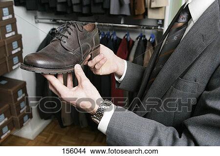 Side view of a man holding a shoe in his hands in a retail store View Large Photo Image Picture - Side view of a man holding a shoe in his hands in a retail store. Fotosearch