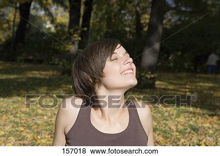 A young woman relaxing in a park, smiling View Large Photo Image Stock Photo - A young woman relaxing in a park, smiling. Fotosearch