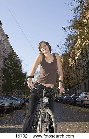 Stock Image - Front view of a young woman on a bicycle. Fotosearch
