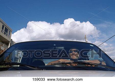 A man sits in a parked car View Large Photo Image Stock Image - A man sits in a parked car. Fotosearch