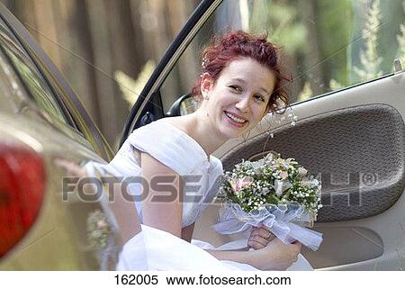Stock Photography - A bride holding a bouquet while sitting in a car. Fotosearch