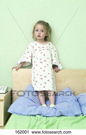 A young girl standing on a bed View Large Photo Image Stock Image - A young girl standing on a bed. Fotosearch