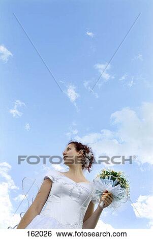 Low angle view of a bride holding a bouquet of flowers View Large Photo Image Stock Photograph - Low angle view of a bride holding a bouquet of flowers. Fotosearch