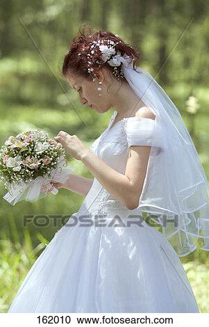 Stock Image - Side view of a bride holding a bouquet. Fotosearch
