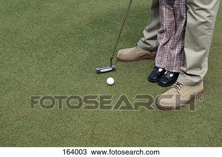 Stock Image - A man teaching a child how to putt. Fotosearch