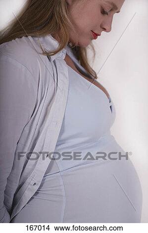 Picture - A pregnant woman smiling as she looks at her stomach. Fotosearch