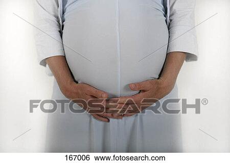 Midsection of a pregnant woman holding her stomach View Large Photo Image Stock Photograph - Midsection of a pregnant woman holding her stomach. Fotosearch