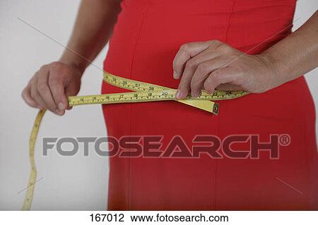 Midsection of a pregnant woman measuring her waist with a measuring tape View Large Photo Image Stock Image - Midsection of a pregnant woman measuring her waist with a measuring tape. Fotosearch