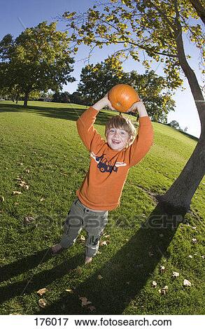 Stock Photo - A young boy holding a pumpkin over his head. Fotosearch
