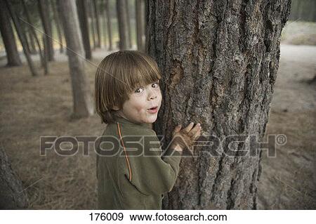 Stock Photo - A young boy holding on to a tree. Fotosearch