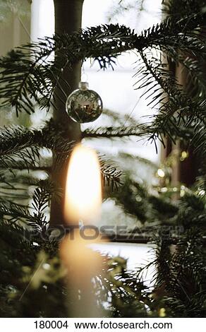 Christmas tree with silver decoration and burning candle View Large Photo Image Picture - Christmas tree with silver decoration and burning candle. Fotosearch