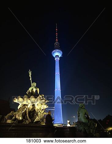 Stock Image - Television tower and statue of Neptune illuminated at night, Berlin, Germany. Fotosearch