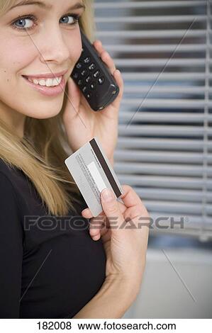 Young woman on telephone and holding credit card View Large Photo Image Stock Photo - Young woman on telephone and holding credit card. Fotosearch