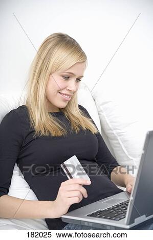 Young woman sitting and holding credit card in front of laptop View Large Photo Image Stock Photography - Young woman sitting and holding credit card in front of laptop. Fotosearch