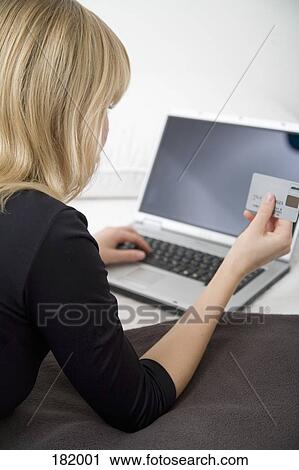 Young woman using a credit card online with her laptop View Large Photo Image Stock Image - Young woman using a credit card online with her laptop. Fotosearch