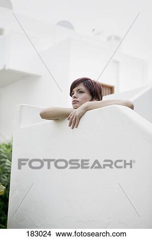 Young woman leaning on wall of luxury tourist resort and looking away View Large Photo Image Picture - Young woman leaning on wall of luxury tourist resort and looking away. Fotosearch