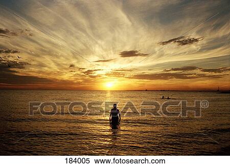 Man standing in sea at sunset View Large Photo Image Stock Photography - Man standing in sea at sunset. Fotosearch