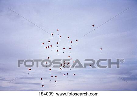 Stock Photo - Red heart shaped balloons floating in the sky. Fotosearch