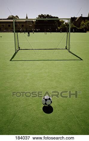 Soccer ball in front of goal with players training in background View Large Photo Image Stock Photo - Soccer ball in front of goal with players training in background. Fotosearch