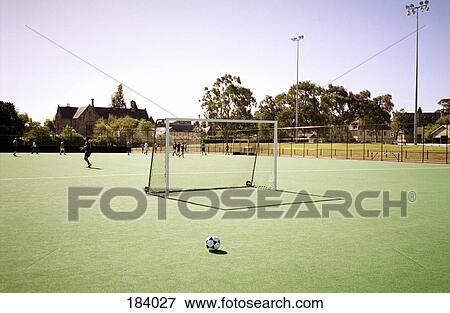 Soccer ball on soccer field with people training in background View Large Photo Image Stock Photo - Soccer ball on soccer field with people training in background. Fotosearch