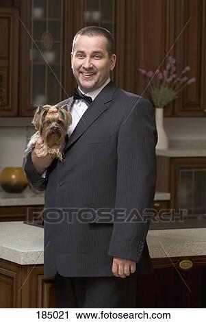 Stock Image - Man dressed in suit and holding lap dog. Fotosearch